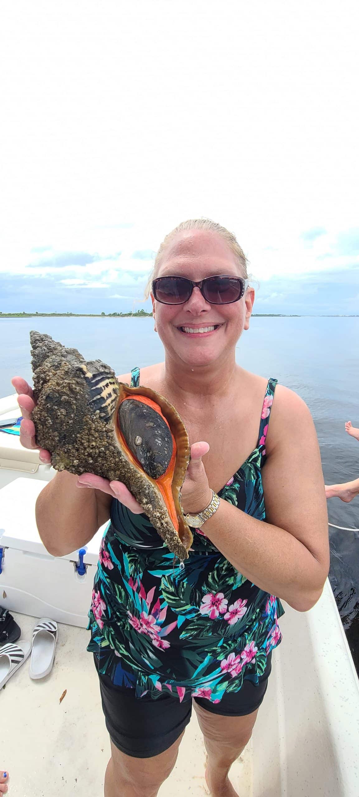 Woman holding a large conch shell she found while on a private boat tour with Anchor Charters in Panama City