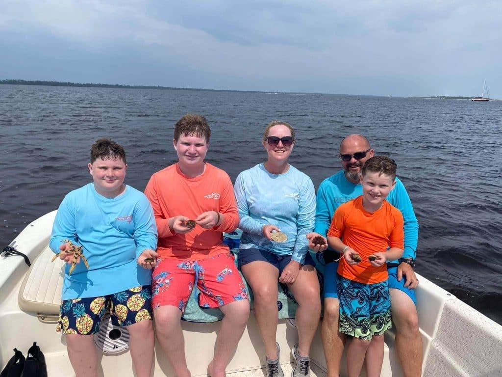 Family of five holding up sand dollars and star fish they found in the Gulf of Mexico with Anchor Charters